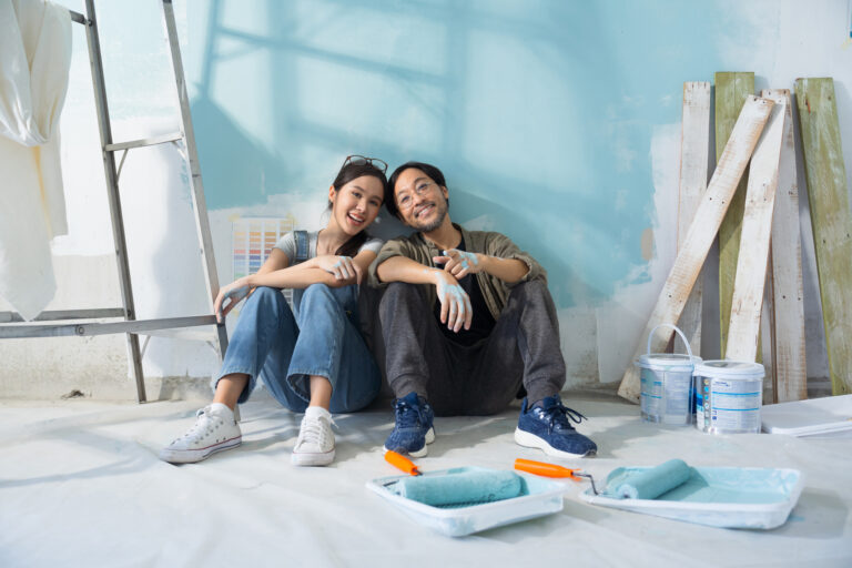 Couple renovating their home by painting the walls.